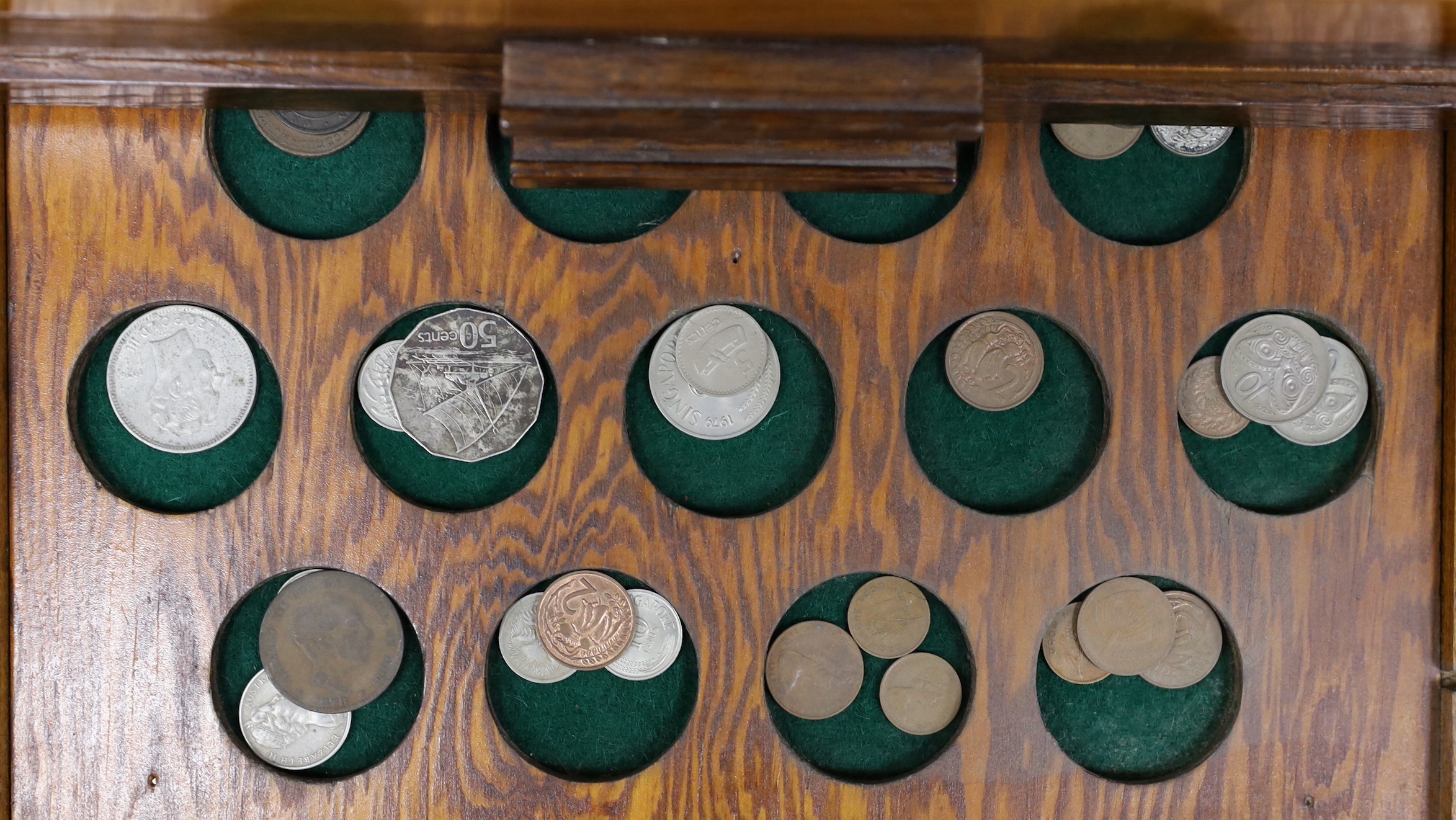 A collection of mixed coinage in a collectors cabinet, 27cm tall